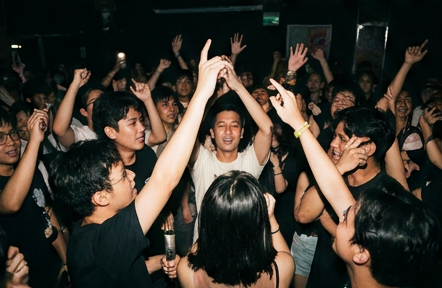 A packed crowd with hands raised at an Amplify jam